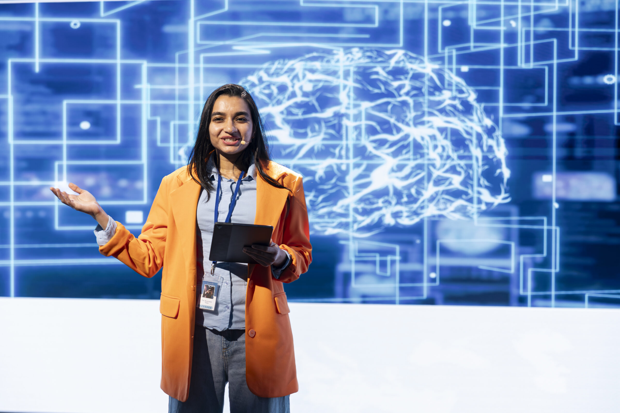 Cheerful engineer holding presentation at AI tech summit event gathering professionals using tablet. Jolly speaker using device to present how can AI be leveraged to accelerate innovation